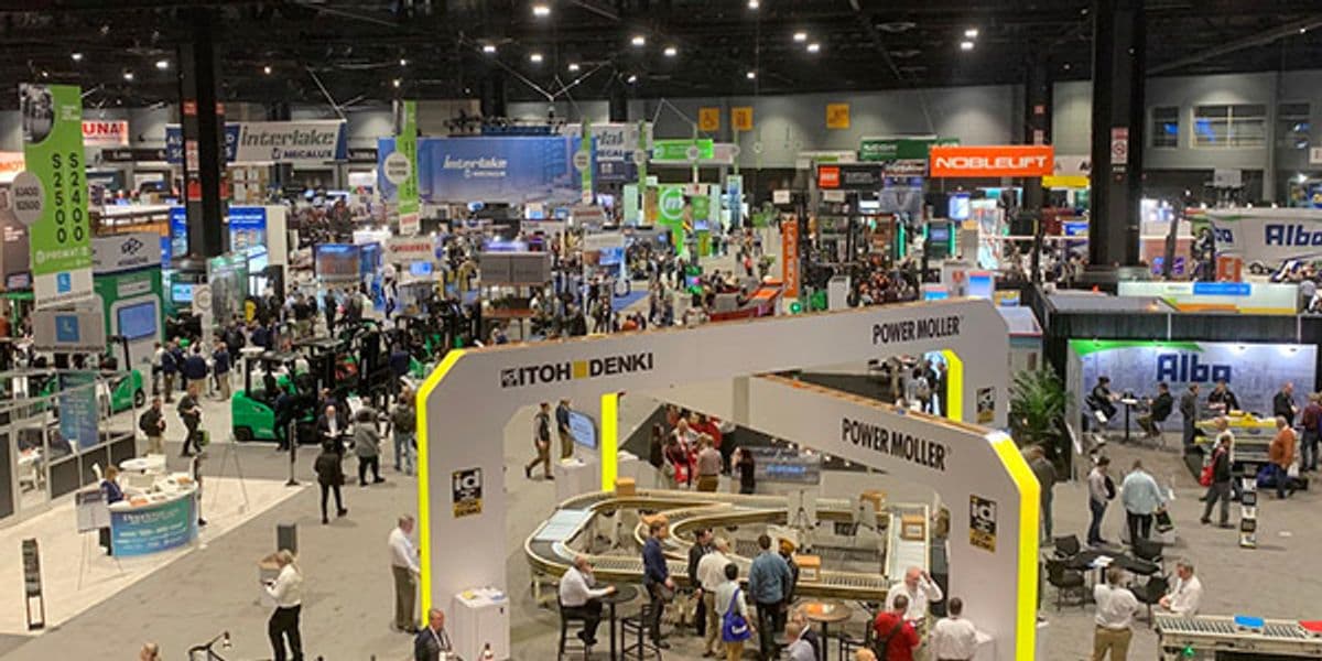 Busy exhibition hall at a supply chain and logistics trade show with attendees and expo booths.