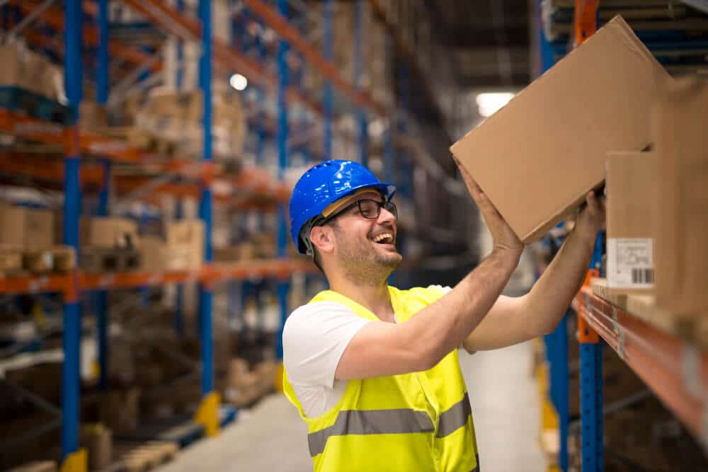 Smiling Warehouse Worker Moving Boxes Shelf